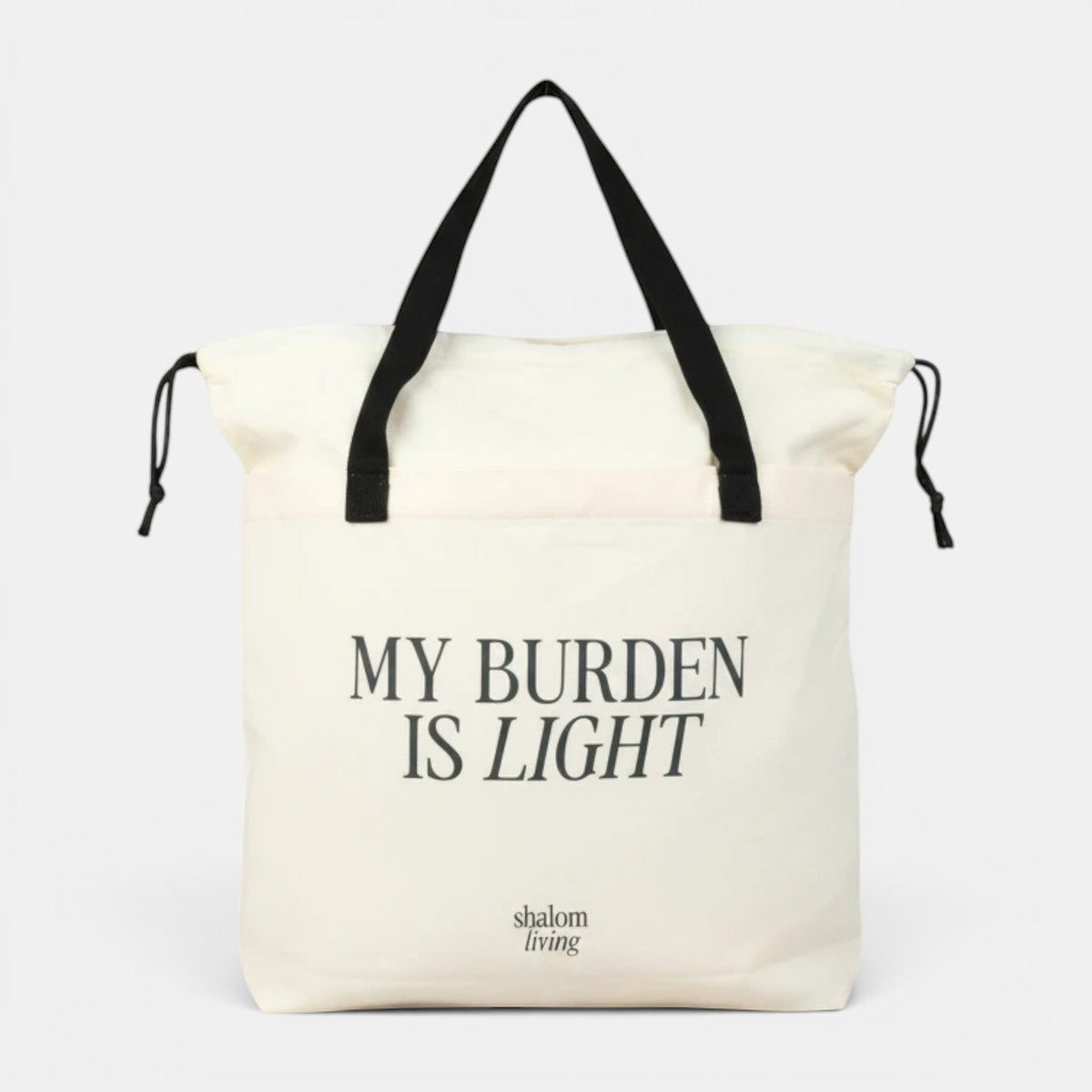 Shalom Living My Burden Is Light canvas tote bag with black handles and drawstring closure. Spacious everyday carry.