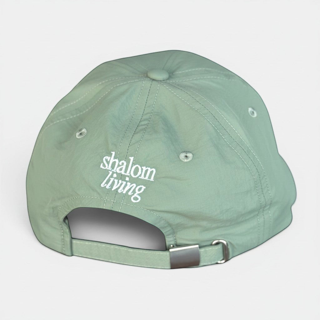 Shalom Living sage green lightweight adjustable outdoor cap with embroidered logo on back. Breathable fabric for everyday wear.