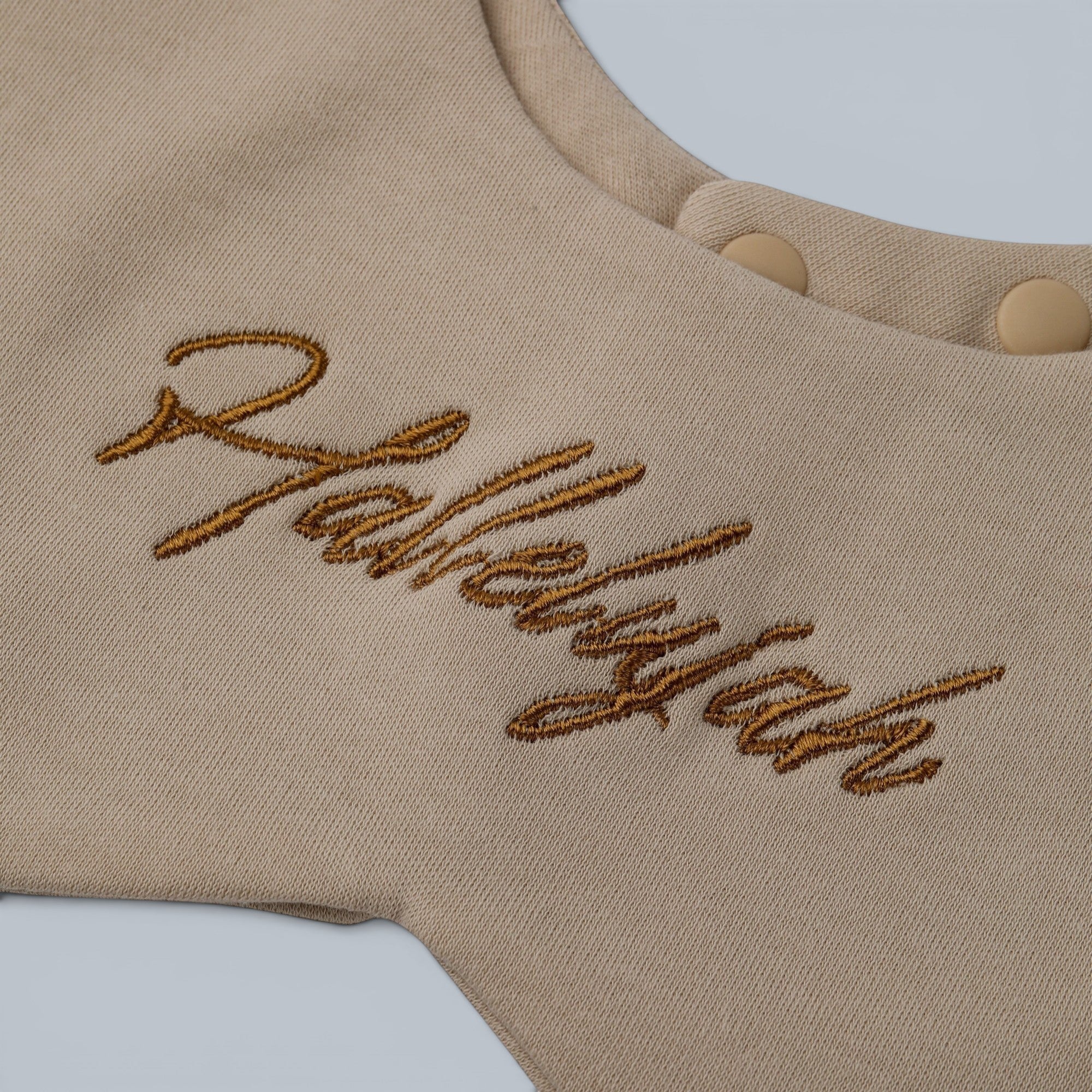 Shalom Living sand-colored cotton baby bib with