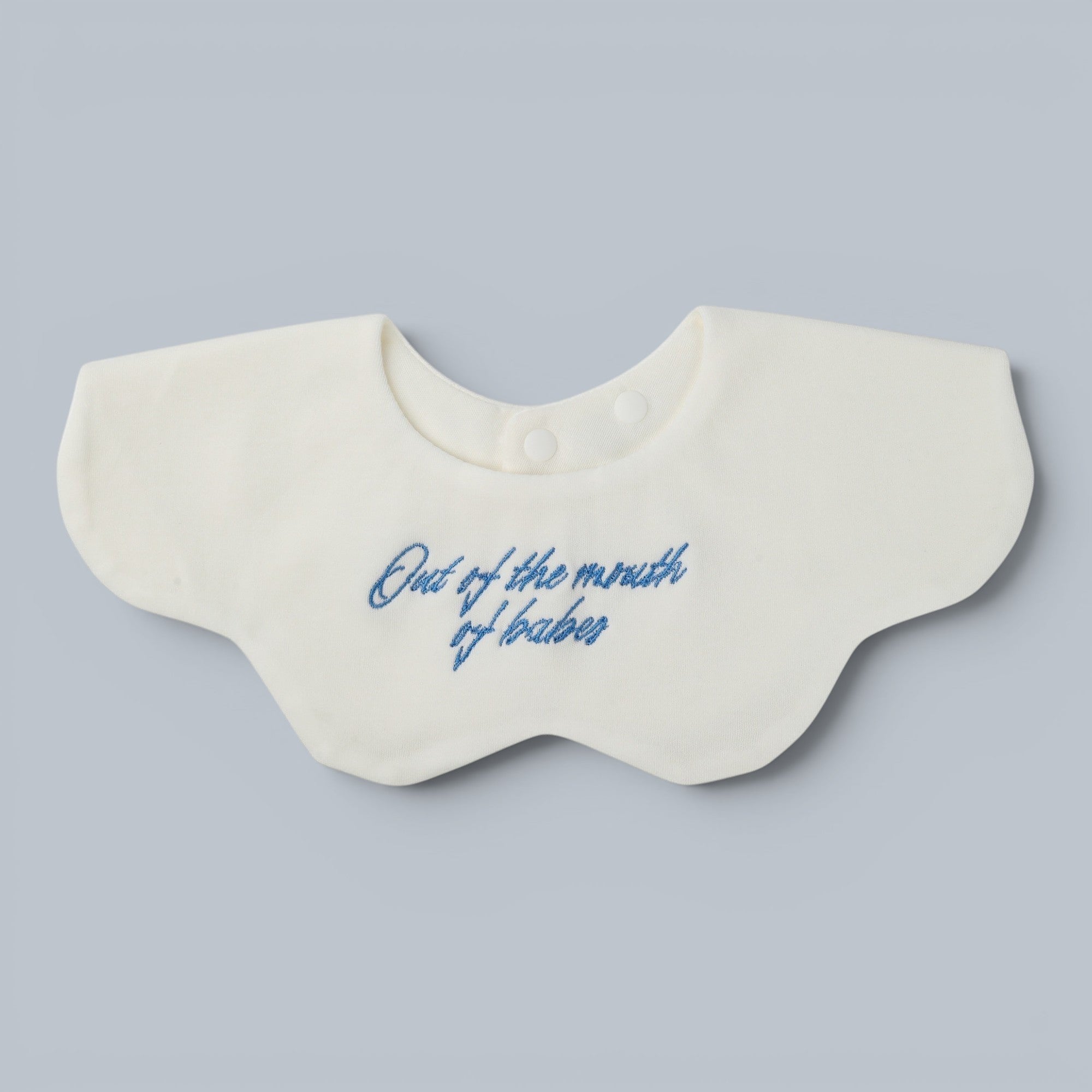 Shalom Living white petal baby bib with blue embroidered text "Out of the mouth of babes".