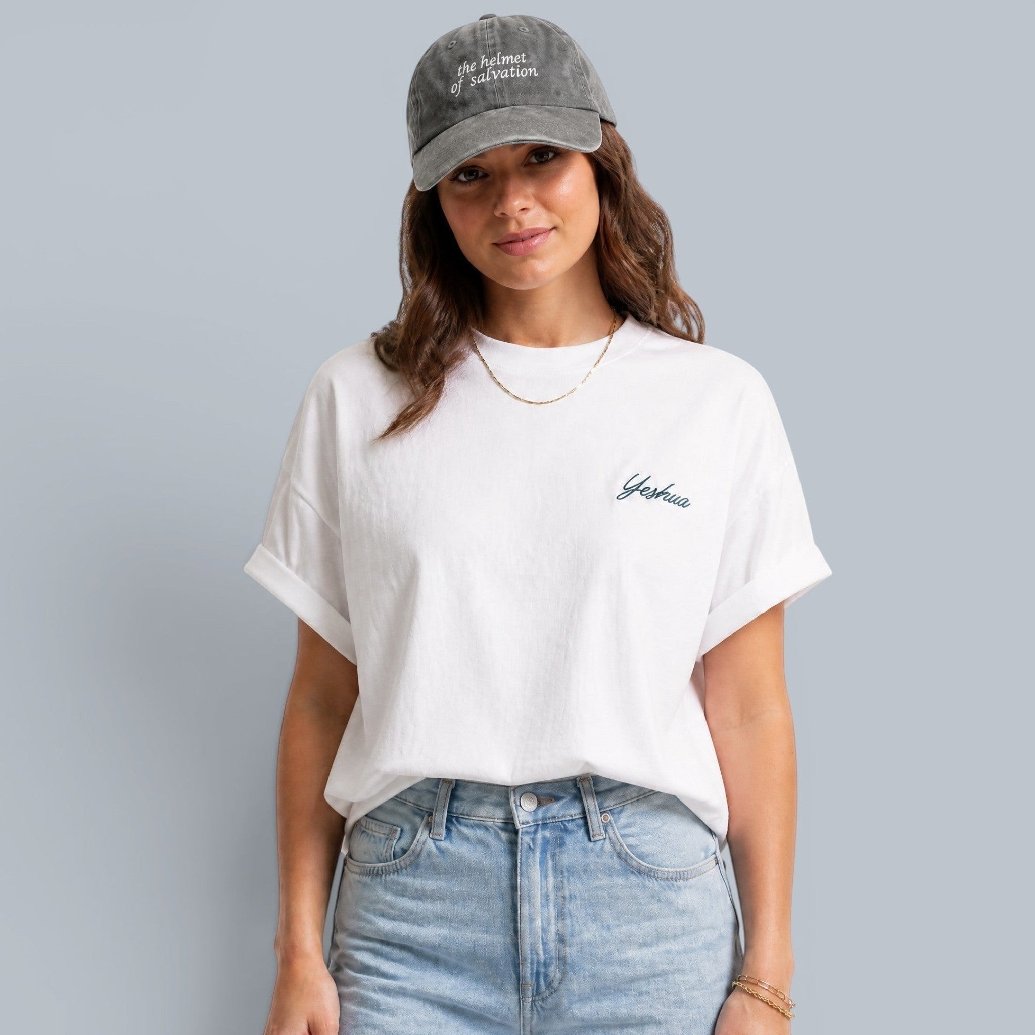 Shalom Living white cotton boxy t-shirt with blue Yeshua embroidery on the chest and cuffed sleeves. Model wears light wash jeans.