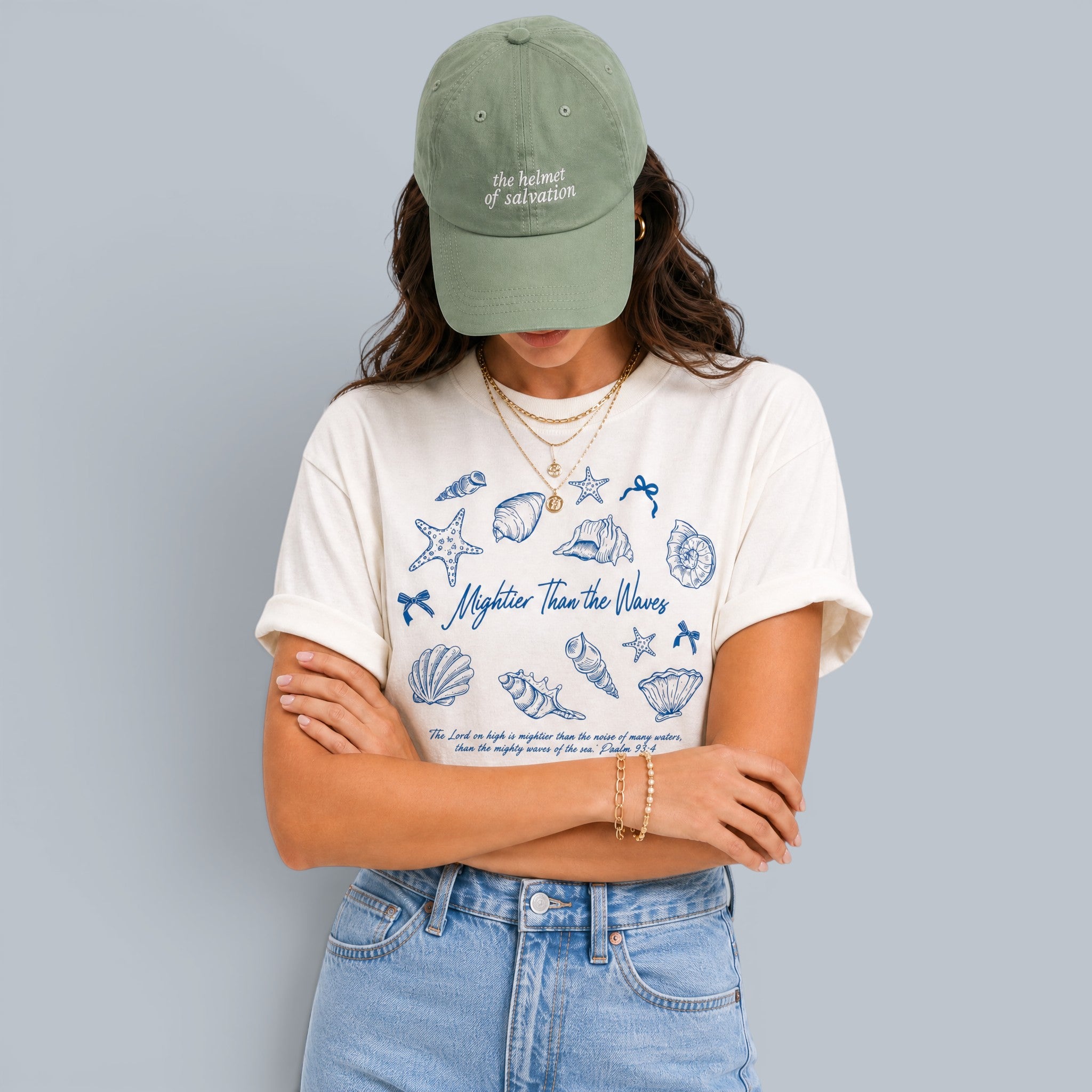Shalom Living cream relaxed fit t-shirt with blue seashell graphic and text "Mightier Than The Waves".