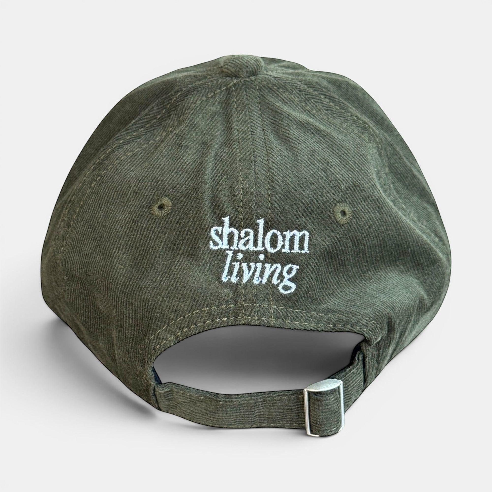 Shalom Living olive green corduroy cap with adjustable strap and embroidered text on back.