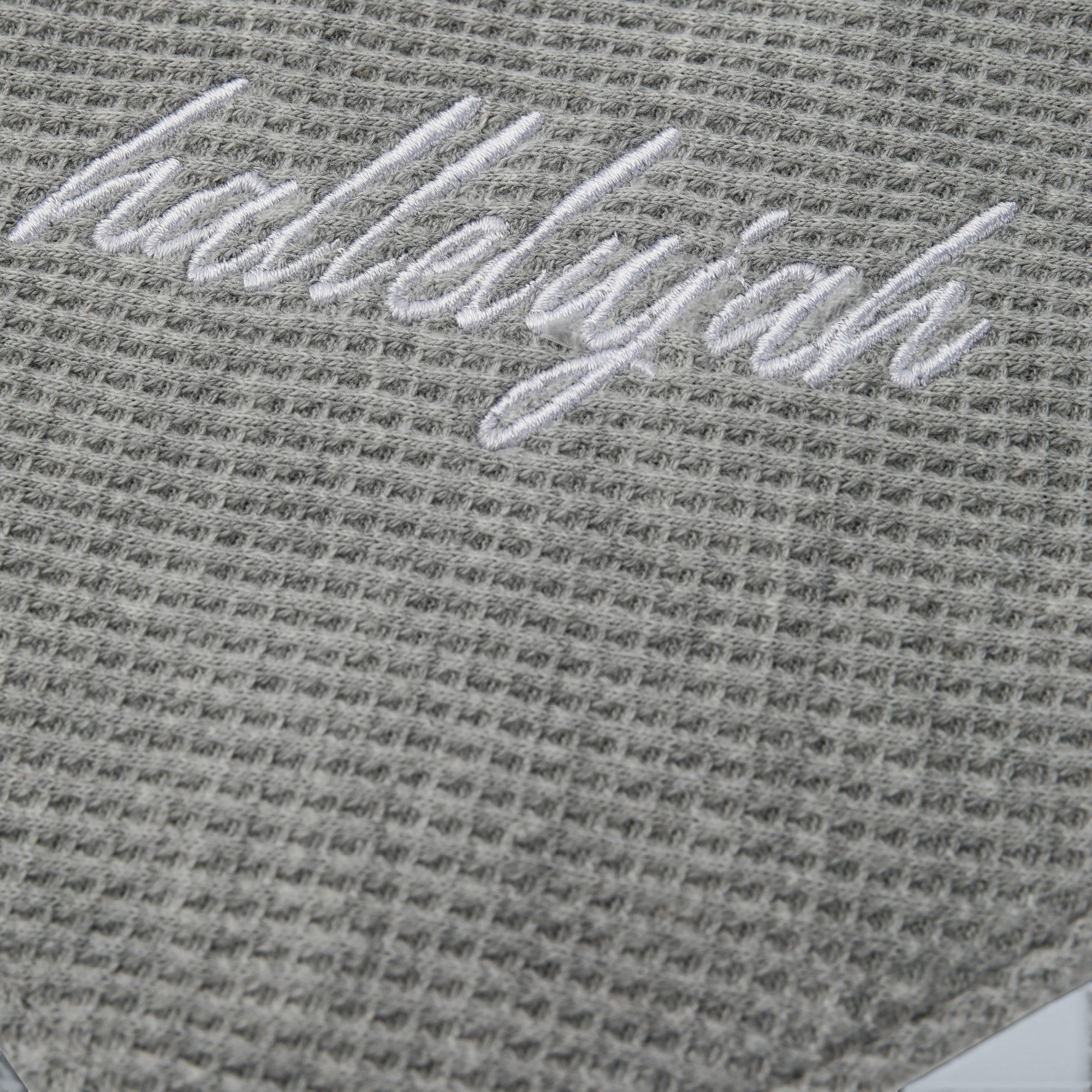 Shalom Living grey waffle bandana bib with white "hallelujah" embroidery and snap closure.