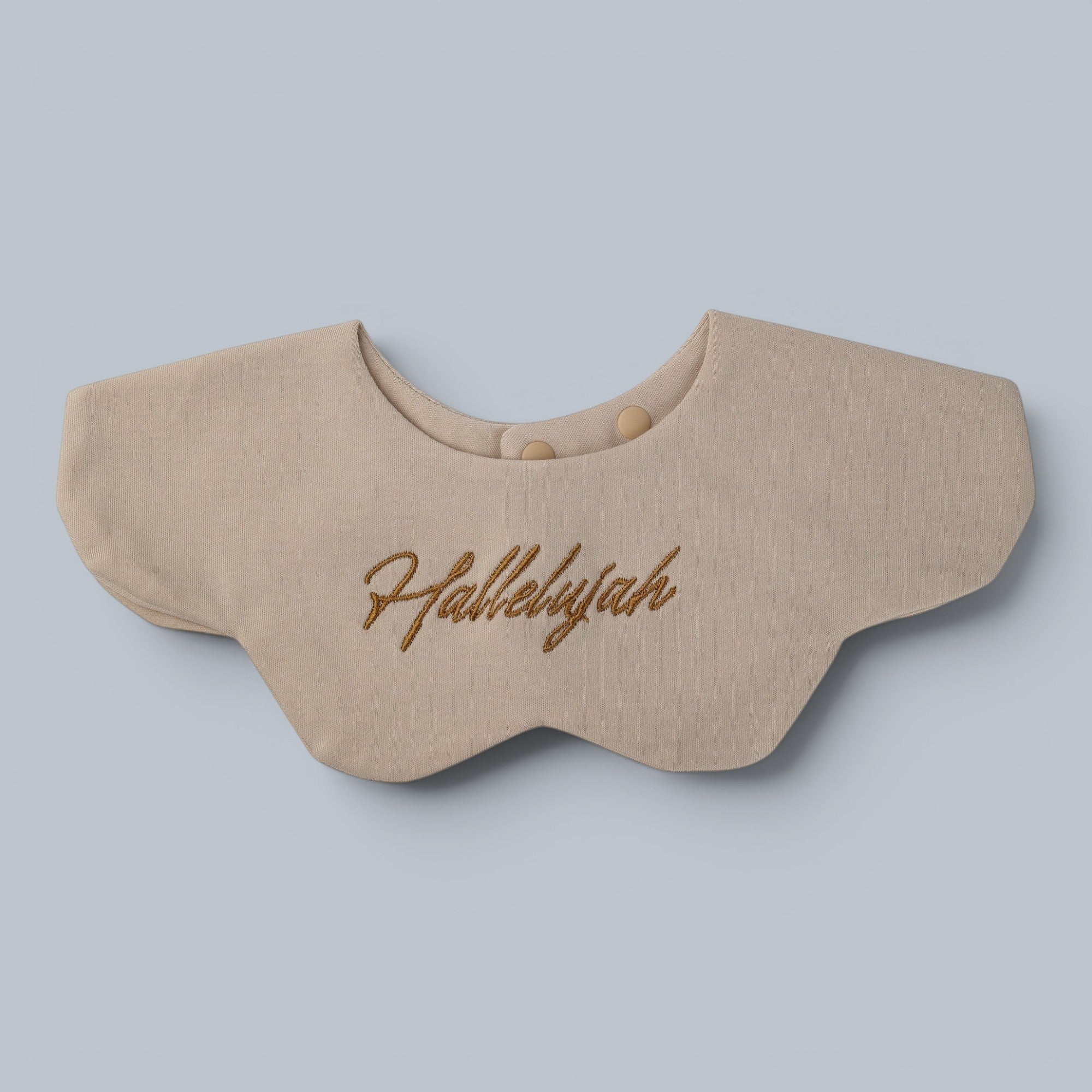 Shalom Living sand-colored petal bib with "Hallelujah" embroidery and snap closure. Soft cotton with waterproof layer.