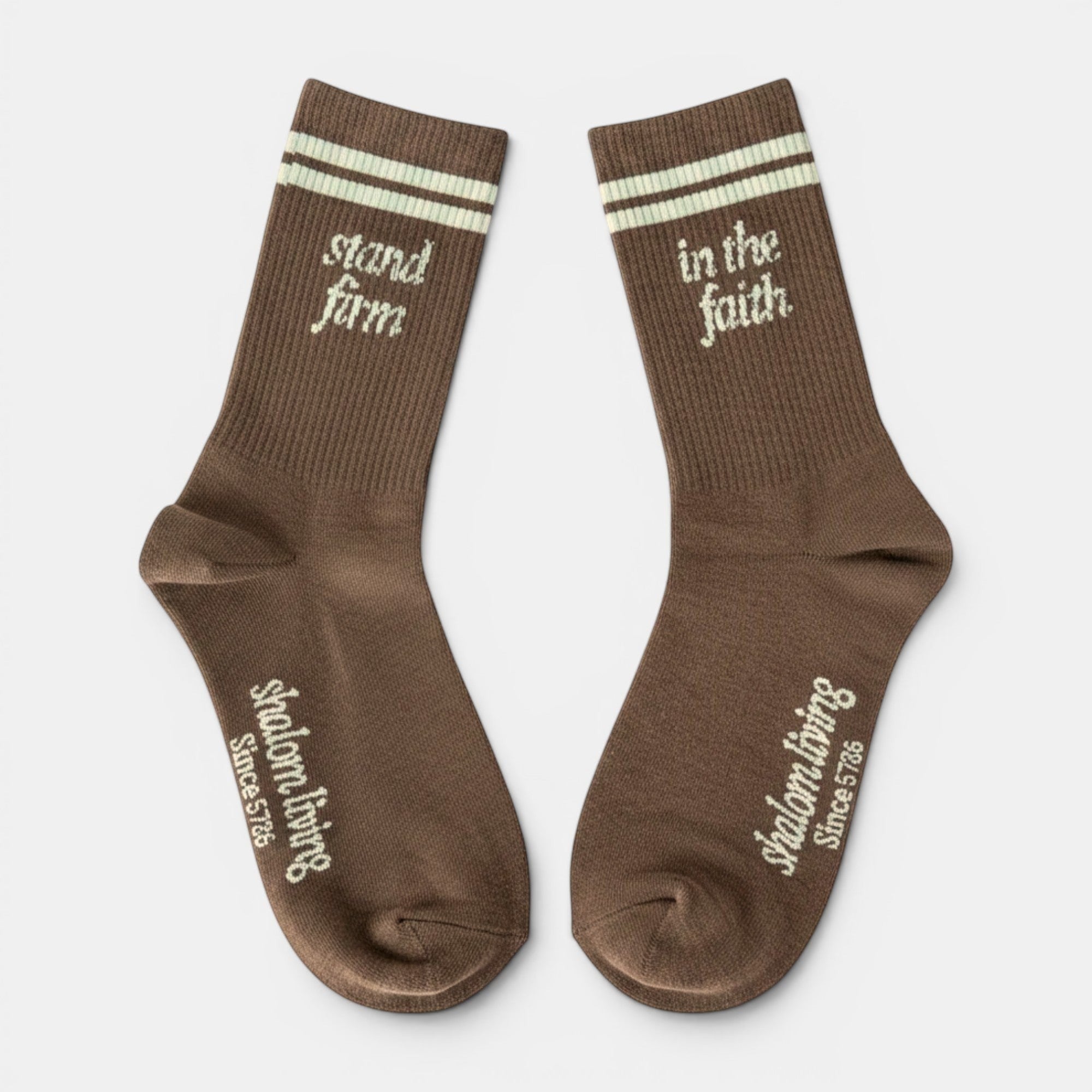 Shalom Living brown crew socks with light blue stripes and "stand firm" / "in the faith" text.